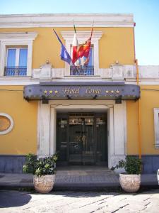 Hotel Como في سيراكوزا: مبنى الفندق مع وجود علامتين أمامه