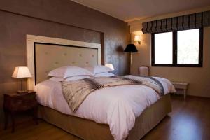 a bedroom with a large bed with white sheets and pillows at Valis Resort Hotel in Volos