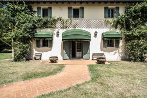 ミネルビオにあるIl Borgo di Minervaの緑の日よけとパティオ付きの白い家