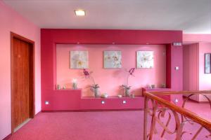 Zimmer mit rosa Wänden, einem Tisch und Blumen in der Unterkunft Family Hotel Mania in Stara Sagora