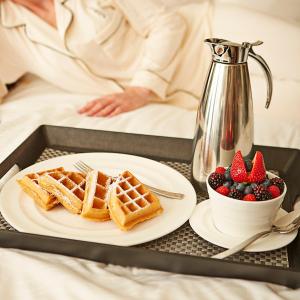 a tray with a plate of waffles and a bowl of berries at Fontainebleau Miami Beach in Miami Beach