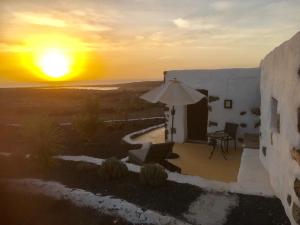 ein Sonnenuntergang über dem Meer von einem Haus mit einem Regenschirm in der Unterkunft "Ziegenstall" mit Meerblick in Yaiza