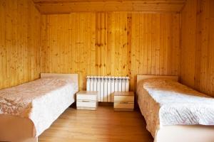 two beds in a room with wooden walls and wooden floors at Villa Premium Qusar in Qusar