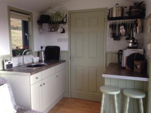 a kitchen with a sink and a counter with stools at Upper Gilwern Quarry Hut in Llandrindod Wells