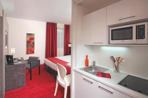 a hotel room with a bed and a kitchen with a sink at Appart'City Confort Grenoble Inovallée in Montbonnot-Saint-Martin