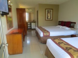 a hotel room with two beds and a television at Capricorn International Hotel in Nadi
