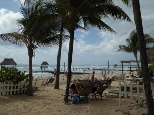 a beach with people sitting in chairs and palm trees at Suites at Mayan Palace Vidanta Resort Riviera Maya in Playa del Carmen