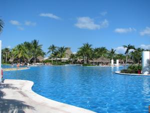 una piscina en un complejo con palmeras en Suites at Mayan Palace Vidanta Resort Riviera Maya en Playa del Carmen
