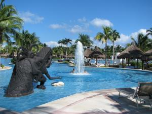 a fountain in the middle of a swimming pool at a resort at Suites at Mayan Palace Vidanta Resort Riviera Maya in Playa del Carmen
