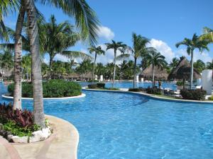 een zwembad in een resort met palmbomen bij Suites at Mayan Palace Vidanta Resort Riviera Maya in Playa del Carmen