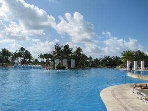 a large swimming pool with palm trees in the background at Suites at Mayan Palace Vidanta Resort Riviera Maya in Playa del Carmen