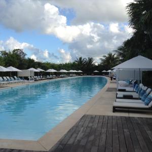 a large swimming pool with lounge chairs and umbrellas at Suites at Mayan Palace Vidanta Resort Riviera Maya in Playa del Carmen