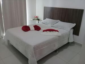 a large white bed with two red pillows on it at Trevo De Arraial pousada em cabo frio in Cabo Frio