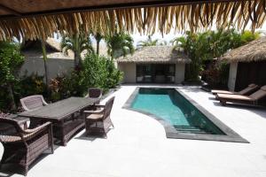 a patio with a table and a swimming pool at Te Manava Luxury Villas & Spa in Rarotonga