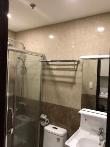 a bathroom with a glass shower and a toilet at Umali Kayo at Megatower Residences II in Baguio