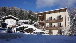 a man standing in front of a building covered in snow at Yonagoya in Kami