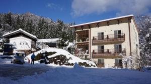 un homme debout devant un bâtiment recouvert de neige dans l'établissement Yonagoya, à Kami