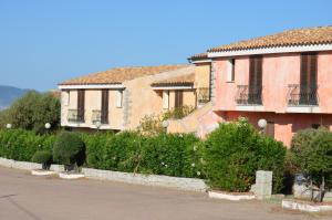 un bâtiment avec une rangée de buissons à côté d'une rue dans l'établissement Residence Costa Del Turchese, à Badesi