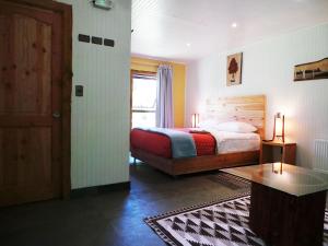 1 dormitorio con cama, mesa y puerta en Treca Rupan Lodge en Neltume