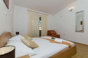 una camera con un grande letto bianco e una sedia di Apartments Srecko a Duće