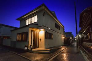 a white building with a door on a street at night at Marikoji Inn Kyoto in Kyoto