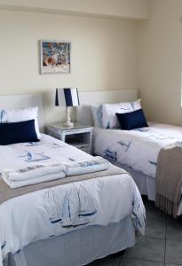 two beds in a room with white sheets at 605 Nautica in Bloubergstrand