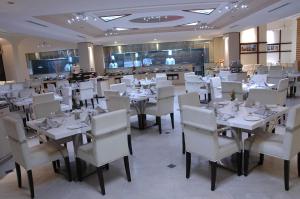 a dining room with white tables and white chairs at Sandesh Pride in Mysore