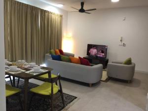 a living room with a couch and a table with a tv at Afiniti Muslim Medini Condo in Nusajaya