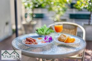 a table with a plate of food and a glass of orange juice at Baanthanam Nont in Nonthaburi