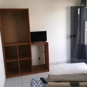 a living room with a tv and a book shelf at Pousada Amazonas in Itabuna