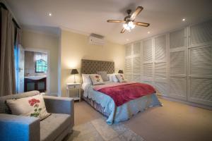 a bedroom with a bed and a couch and a ceiling fan at Boutique Villa Guesthouse in Somerset West