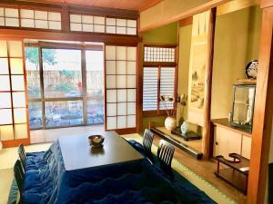 ein Esszimmer mit einem Tisch, Stühlen und einem Fenster in der Unterkunft Guesthouse Kyoto Arashiyama in Kyoto