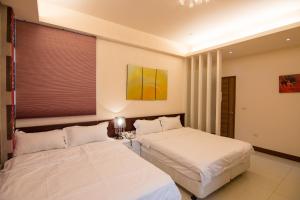 馬公市的住宿－達日好民宿 ，配有白色床单的酒店客房内的两张床