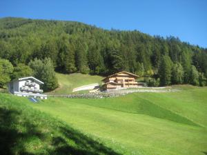 a house on the side of a green hill at Beim Untertimmeltaler in Matrei in Osttirol