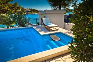 a blue swimming pool with a chair next to it at Delux Villa Hedonica in Zaboric