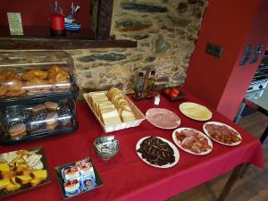 a table with a red table cloth with different types of food at Hotel Rural Pescadores in Sobrado