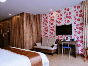 a hotel room with a bed and a chair and a television at A Ace Hotel in Taichung