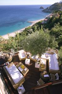 una terraza con mesas y sillas y una playa en Hotel Claudio, en Bergeggi