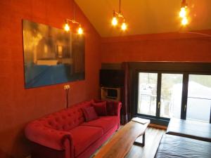 salon z czerwoną kanapą i telewizorem w obiekcie The Roots w mieście Marcouray