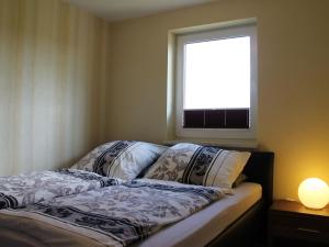 Bett in einem Zimmer mit Fenster und Lampe in der Unterkunft Sunlit Holiday Home with Fenced Garden in Bastorf in Bastorf