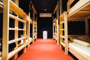 Habitación con literas de madera y alfombra roja. en Hostel Mange Tak en Hiroshima