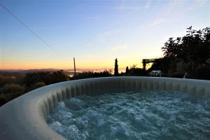 a hot tub in a backyard with the sunset in the background at Villa La Moraiola in Passignano sul Trasimeno