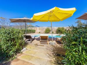 una sombrilla y sillas amarillas y una piscina en Belvilla by OYO Villa 13, en Consell
