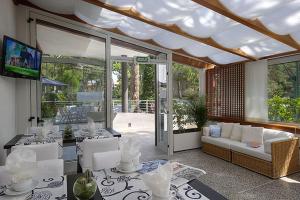 リニャーノ・サッビアドーロにあるSuite Erica Lignano Hotelのソファとテーブルと椅子のあるリビングルーム