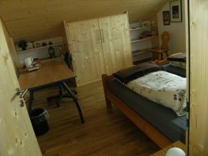um quarto com uma cama, uma secretária e uma mesa em BnB Niederer em La Côte-aux-Fées