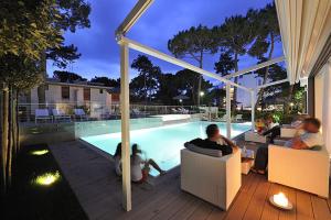 a group of people sitting next to a swimming pool at Suite Erica Lignano Hotel in Lignano Sabbiadoro