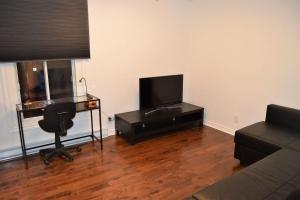 sala de estar con TV y silla en BnbEra - The Rock Apartment, en Montreal