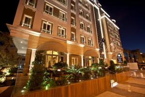 un grand bâtiment avec des tables et des plantes devant lui dans l'établissement Zubarah Hotel, à Doha