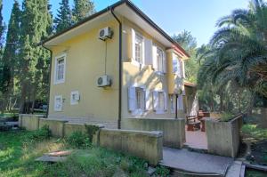 een geel huis met een hek ervoor bij Rosemary Apartments & Rooms in Mali Lošinj