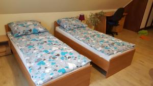 two twin beds in a room with a desk at Domek u Darka in Kielce